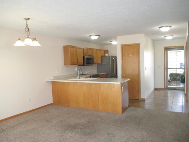 kitchen featuring light colored carpet, light countertops, a peninsula, brown cabinetry, and stainless steel appliances