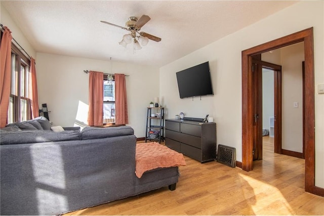 living area with light wood-style flooring, baseboards, a wealth of natural light, and ceiling fan