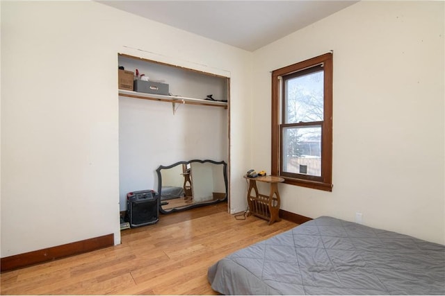 bedroom featuring light wood-type flooring, baseboards, and a closet