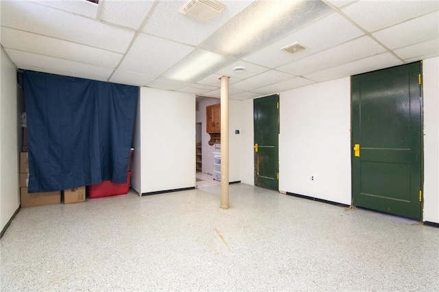 empty room featuring a drop ceiling, speckled floor, and baseboards