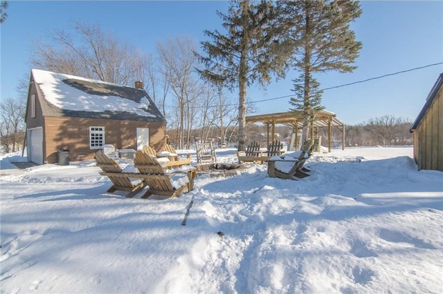 yard covered in snow featuring a garage and an outbuilding