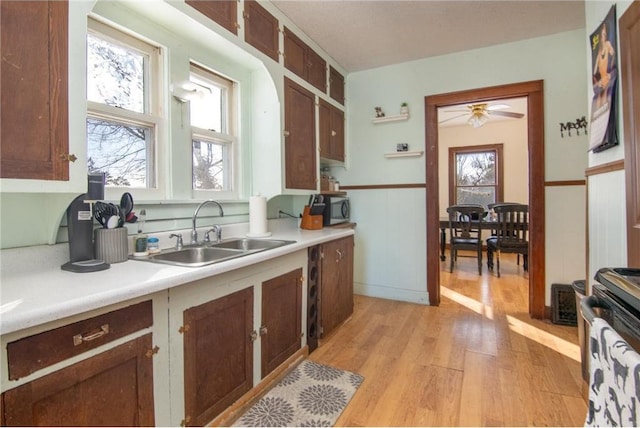 kitchen featuring light wood finished floors, open shelves, light countertops, and a sink