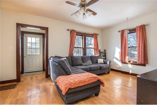 living area with visible vents, light wood-type flooring, and baseboards