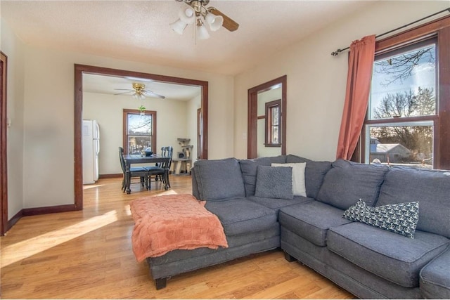 living room featuring a ceiling fan, light wood-style floors, and baseboards