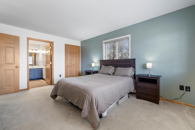 bedroom featuring ensuite bath, light colored carpet, and baseboards