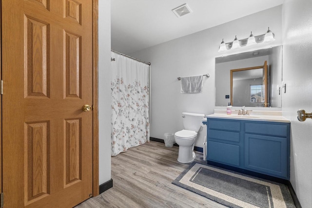 bathroom with visible vents, baseboards, toilet, wood finished floors, and vanity