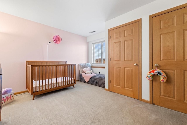 carpeted bedroom featuring visible vents, a crib, and baseboards