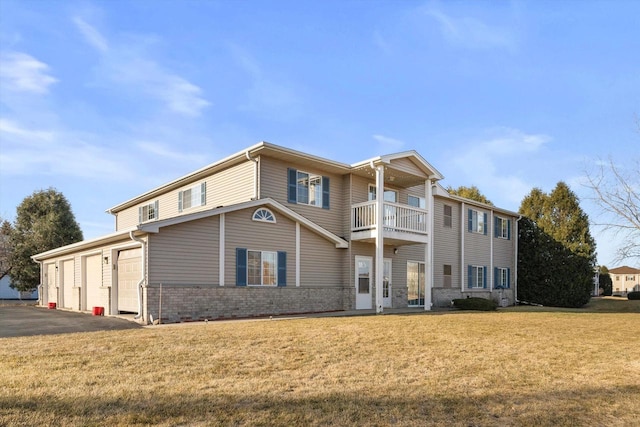 view of front of house featuring brick siding, aphalt driveway, a front yard, a garage, and a balcony