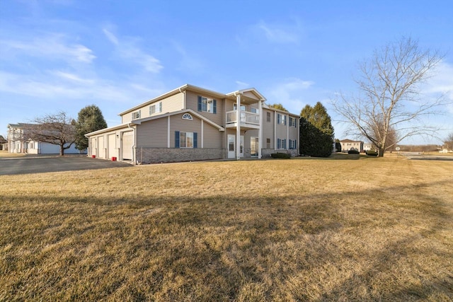 exterior space with a balcony, a garage, a lawn, and brick siding