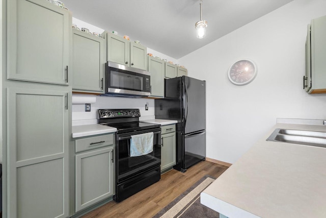 kitchen with black appliances, wood finished floors, light countertops, and a sink