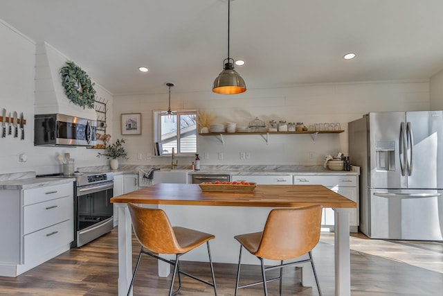 kitchen featuring a breakfast bar, stainless steel appliances, dark wood-style floors, white cabinetry, and wood counters