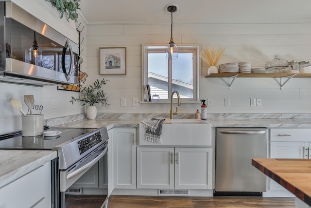 kitchen featuring open shelves, a sink, white cabinets, appliances with stainless steel finishes, and decorative light fixtures