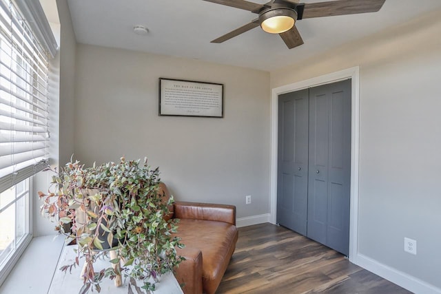 living area with dark wood finished floors, a ceiling fan, and baseboards