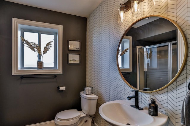 bathroom with a sink, baseboards, toilet, and a shower with door