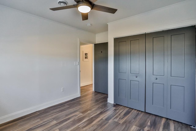 unfurnished bedroom featuring dark wood finished floors, baseboards, a closet, and a ceiling fan