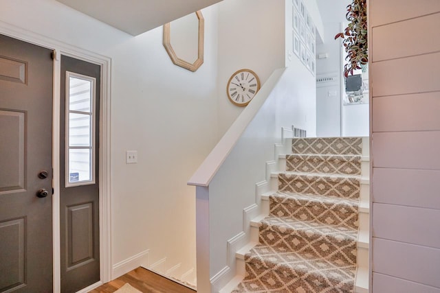 foyer entrance with stairway and baseboards