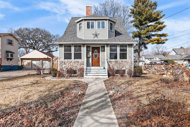 view of front facade featuring a garage, an outbuilding, a chimney, and a shingled roof