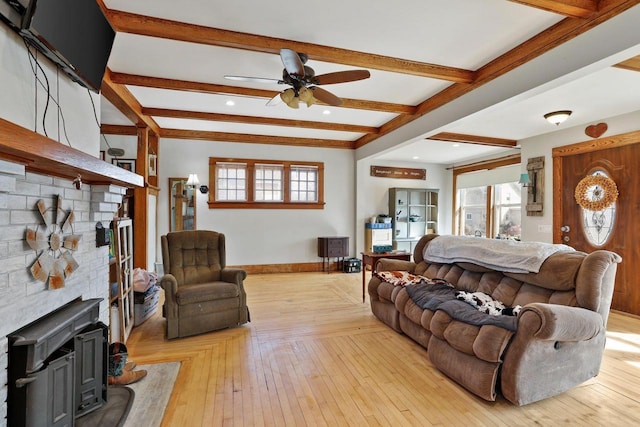 living room featuring beam ceiling, plenty of natural light, baseboards, and light wood-type flooring