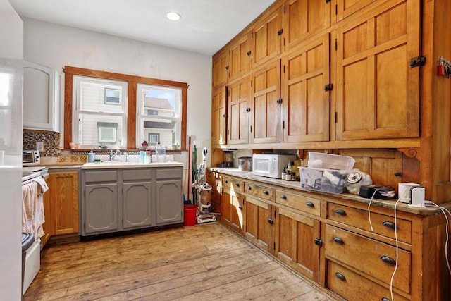 kitchen with white microwave, light wood-type flooring, and brown cabinets