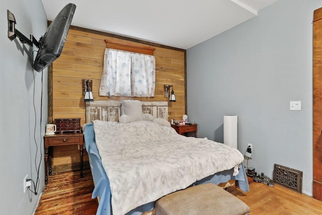 bedroom featuring wooden walls and wood finished floors