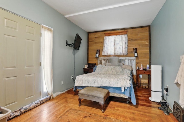 bedroom with wood walls and wood finished floors