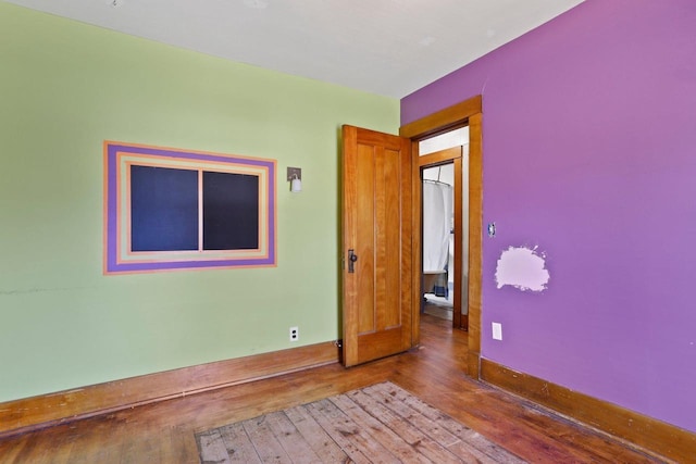 unfurnished room featuring hardwood / wood-style floors and baseboards