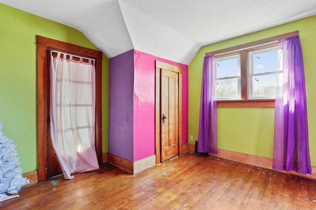 unfurnished bedroom featuring hardwood / wood-style flooring, baseboards, and lofted ceiling