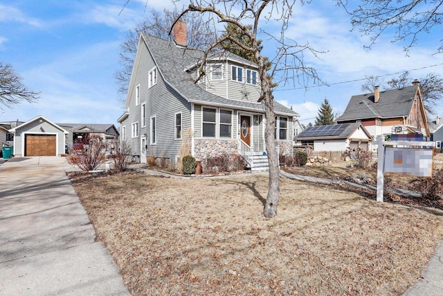 view of front of home with roof with shingles, an outdoor structure, concrete driveway, a garage, and a chimney