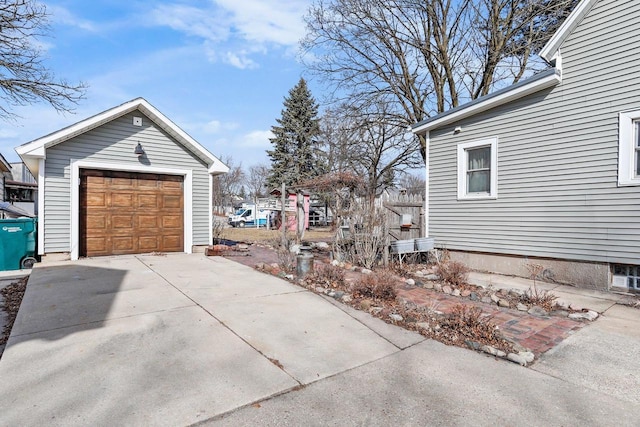 view of property exterior with driveway, a detached garage, and an outdoor structure