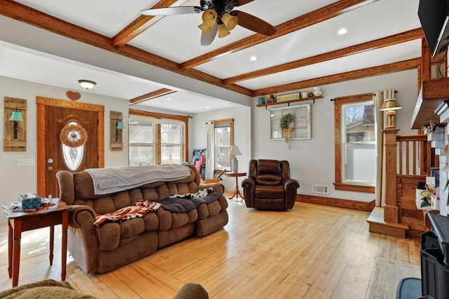 living area featuring baseboards, beam ceiling, visible vents, and light wood-style flooring