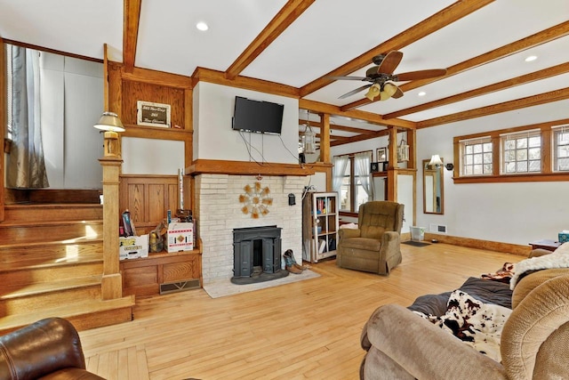 living area with a ceiling fan, wood finished floors, visible vents, baseboards, and beam ceiling