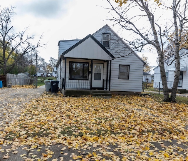 bungalow with a porch, board and batten siding, and fence