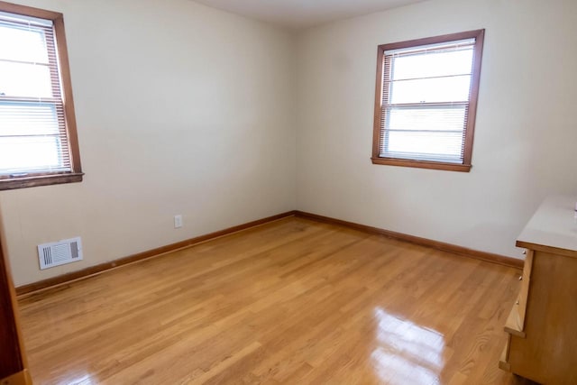 unfurnished room featuring baseboards, visible vents, and light wood-type flooring