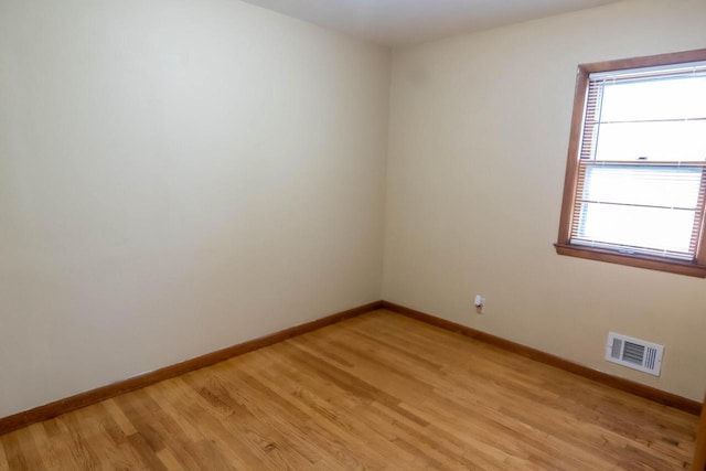 unfurnished room featuring light wood finished floors, visible vents, and baseboards