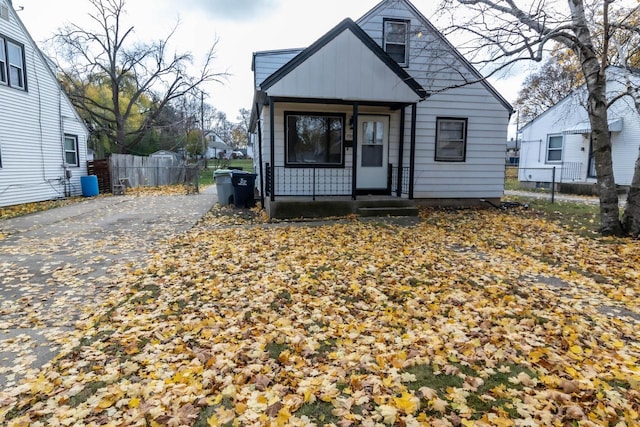 rear view of property with board and batten siding, a porch, and fence