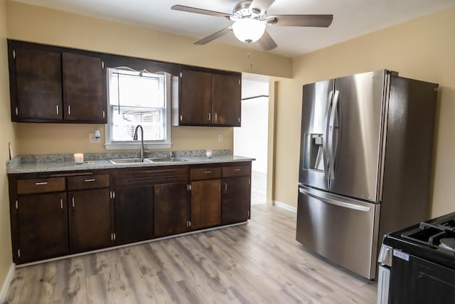 kitchen featuring black gas range oven, stainless steel fridge with ice dispenser, a sink, dark brown cabinets, and light wood-style floors