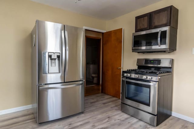 kitchen featuring dark brown cabinetry, light wood-style floors, baseboards, and appliances with stainless steel finishes