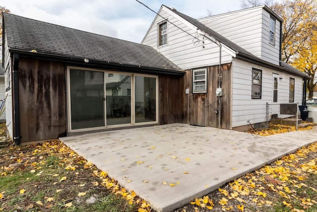 rear view of house featuring a patio area and a shingled roof