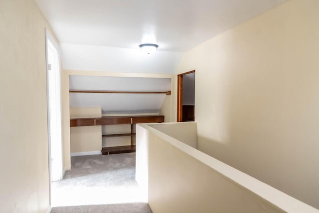 hallway with baseboards, an upstairs landing, carpet, and vaulted ceiling