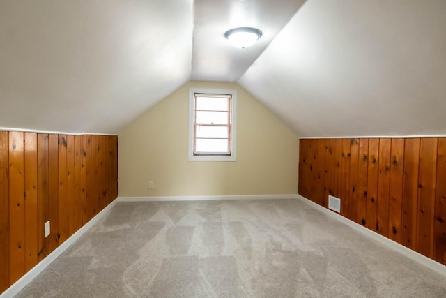 bonus room with visible vents, wood walls, carpet, and vaulted ceiling