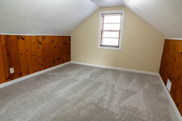 additional living space featuring vaulted ceiling, visible vents, carpet floors, and wood walls