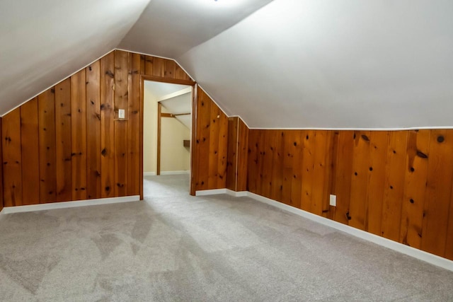 bonus room featuring vaulted ceiling, carpet flooring, baseboards, and wood walls