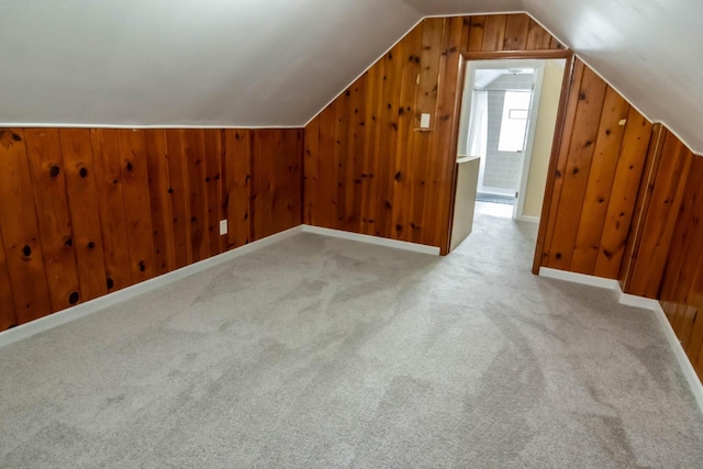 additional living space featuring vaulted ceiling, wooden walls, carpet flooring, and baseboards