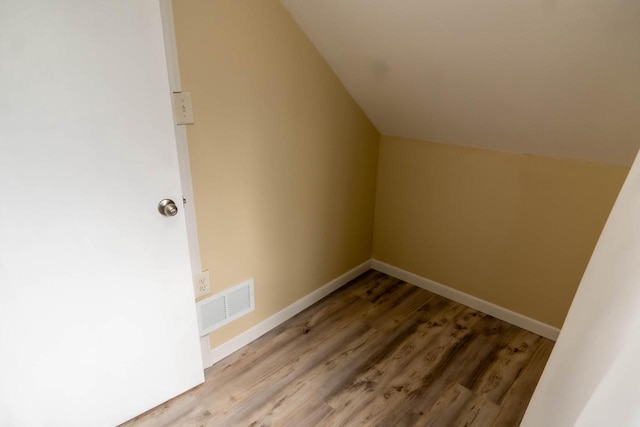 additional living space featuring visible vents, baseboards, wood finished floors, and vaulted ceiling