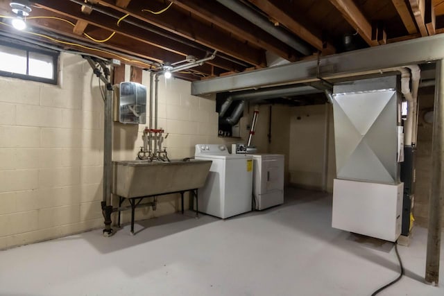 basement with a sink, heating unit, and washer and clothes dryer