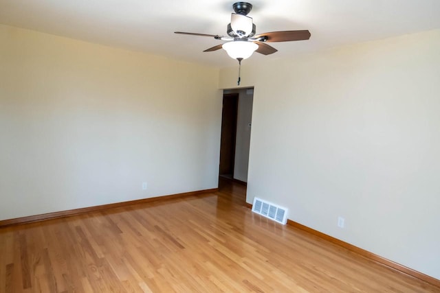 unfurnished room with ceiling fan, light wood-style floors, visible vents, and baseboards