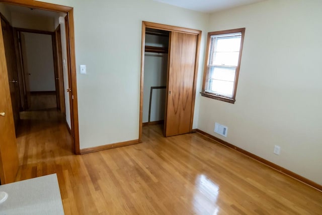 unfurnished bedroom featuring a closet, visible vents, light wood-type flooring, and baseboards