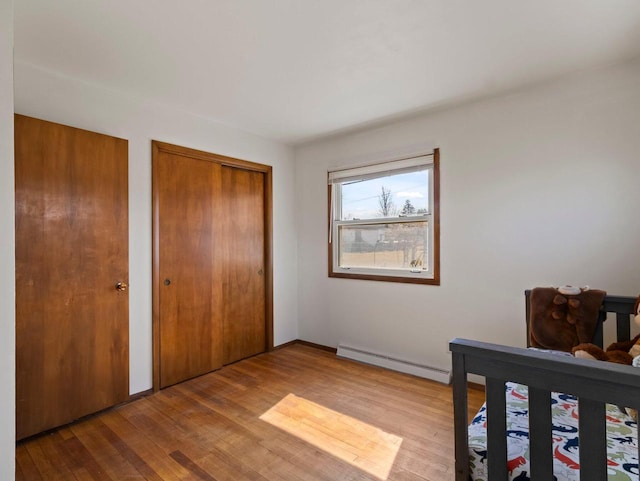 bedroom featuring two closets, hardwood / wood-style floors, and a baseboard radiator