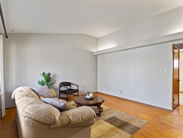 living area featuring baseboards, lofted ceiling, and wood finished floors