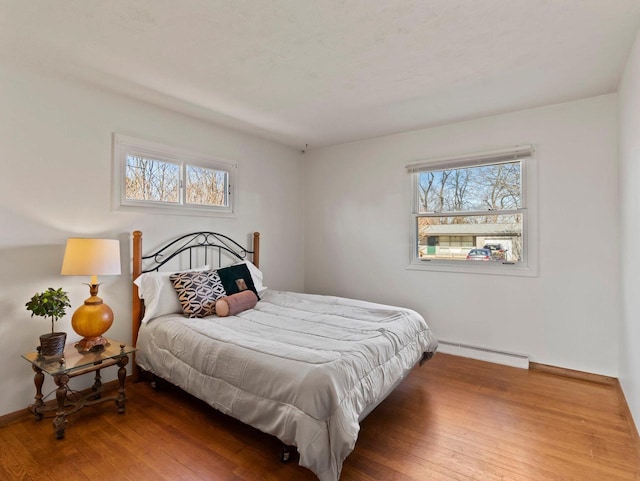 bedroom with hardwood / wood-style floors, baseboards, and a baseboard radiator